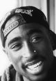 Smiling portrait of Tupac Shakur wearing a cap, showcasing his iconic style and charismatic personality.