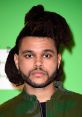 The Weeknd with distinctive hairstyle poses against a bright green background, showcasing his unique style and persona.