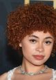 Ice Spice with vibrant curly hair and a stunning necklace, showcasing her unique style and charm at a red carpet event.