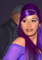 Cardi B showcases vibrant purple hair and bold makeup, exuding confidence at a glamorous event.