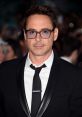 Robert Downey Jr. in a classic black suit with glasses, exuding confidence at a glamorous event, surrounded by fans.