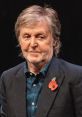 Paul McCartney wearing a blazer and poppy, smiling at an event, showcasing his enduring charm and music legacy.