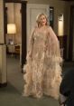Moira Rose dazzles in a glamorous, feathered gown with sequins, exuding elegance and charisma in a cozy setting.