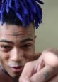 XXXTentacion speaking passionately, showcasing his signature purple hair and expressive gestures. Engaging and dynamic moment captured.