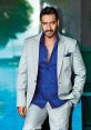 Ajay Devgn in a stylish grey suit and blue shirt, exuding charisma against a modern background.