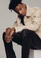 21 Savage poses confidently in a stylish beige jacket, showcasing his unique fashion sense and signature tattoos.