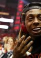 Lil Wayne smiling at a basketball game, showcasing his unique style and bling, with fans in the background.