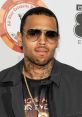 Chris Brown in stylish sunglasses and a black jacket at a celebrity event, showcasing his signature urban fashion.