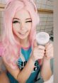 Young woman with pink hair and headphones holding a beauty product, radiating a playful and cheerful vibe.
