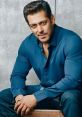 Salman Khan posing confidently in a blue shirt, showcasing his charismatic style and charm in a studio setting.