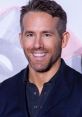 Ryan Reynolds smiles at an event, showcasing his charm and style in a black blazer and casual shirt.