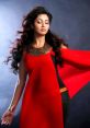 Shreya Ghoshal in a stunning red outfit, showcasing her elegance and grace in a dramatic pose against a dark background.
