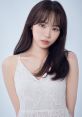 Kim Chaewon from LE SSERAFIM, with long hair, wearing a delicate white dress against a soft blue background.