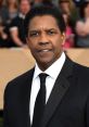 Denzel Washington poses confidently at a red carpet event, showcasing his iconic style and charisma in a classic black suit.