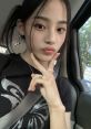 Minji from NewJeans strikes a playful pose in the car, showcasing her style and youthful charm.