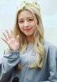 Yuna from ITZY smiling and waving while wearing a crown, showcasing her charming personality and stage presence.