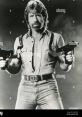 Chuck Norris showcasing his action-hero persona, holding guns, in a dramatic black and white portrait.