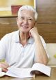 Smiling senior Asian man in a white polo reading documents at a cafe, exuding warmth and wisdom.