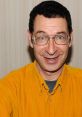 Eddie Deezen smiles brightly, showcasing his iconic Mandark character from "Dexter's Laboratory" in a vibrant yellow shirt.