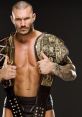 Randy Orton poses confidently, showcasing championship belts, highlighting his status in professional wrestling.