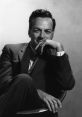 Black and white portrait of physicist Richard Feynman, showcasing his thoughtful expression and engaging smile.