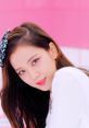 Jisoo poses playfully with soft makeup and a stylish bow, featuring vibrant colors against a pink backdrop.