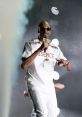 Snoop Dogg performing on stage, wearing sunglasses and a white tracksuit, captivating the audience with his charisma.