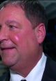 Tony Chimel smiling at an event, showcasing his signature look in formal attire, reflecting his presence in the wrestling community.