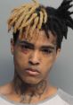 Portrait of a young man with distinctive hairstyle and tattoos, conveying a strong and serious demeanor.