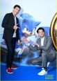 Ben Schwartz and a friend pose at a Sonic The Hedgehog event, featuring the iconic blue character in the background.