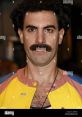 Borat character, portrayed by Sacha Baron Cohen, showcasing a distinctive mustache and colorful outfit at a public event.