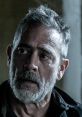 Close-up of Negan Smith from The Walking Dead, showcasing his rugged appearance and intense expression in a dramatic setting.