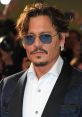 Johnny Depp showcasing his signature style with sunglasses and a navy suit at a high-profile event, exuding charisma.