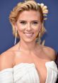 Scarlett Johansson smiles with glamorous makeup, wearing a stunning sequined dress at a red carpet event.