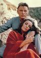Richard Burton and Elizabeth Taylor share an intimate moment, capturing their iconic chemistry in a romantic setting.