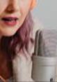 Female ASMR artist engaging with a microphone, creating calming sounds and visuals for relaxation and mindfulness.