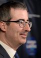 John Oliver at a red carpet event, showcasing his signature glasses and sharp suit, exuding charisma and wit.