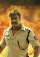 Ajay Devgn as a fierce police officer in Singham, standing against a dramatic fiery backdrop, symbolizing justice and bravery.