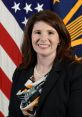 Heidi Smith poses confidently in professional attire against a backdrop of the American flag, showcasing her leadership role.