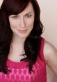 Headshot of Natalie Lynch, featuring her smiling with long dark hair and wearing a vibrant pink top against a soft background.