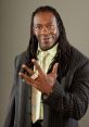 Booker T showcasing his signature hand gesture in stylish attire, embodying confidence and charisma in wrestling.