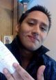 Chad Warden smiling and holding a note with the date, dressed in a stylish black shirt, in a cozy indoor setting.
