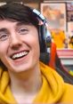 Dawko smiling in a yellow hoodie with headphones, featuring gaming-themed background elements.