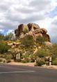 Distinctive boulders rise amidst desert flora near the road, showcasing the natural beauty of the area's landscape.