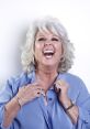 Paula Deen smiling brightly in a light blue blouse, showcasing her signature joyful personality and love for Southern cooking.