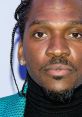Pusha T showcasing a stylish look, featuring a black turtleneck and vibrant blue jacket, exuding confidence at an event.