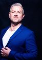 Alex Blackwood in a stylish blue blazer, showcasing confidence and charisma against a dark background.