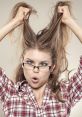 Frustrated woman pulling her hair, expressing wild emotions in plaid shirt and glasses, capturing a moment of madness.