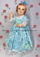Vintage doll dressed in blue lace, adorned with flowers, perfect for collectors and enthusiasts of Jaqui Gonzalez designs.