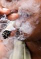 Close-up of a person smoking marijuana, with smoke swirling around a lit joint, highlighting the act of cannabis consumption.